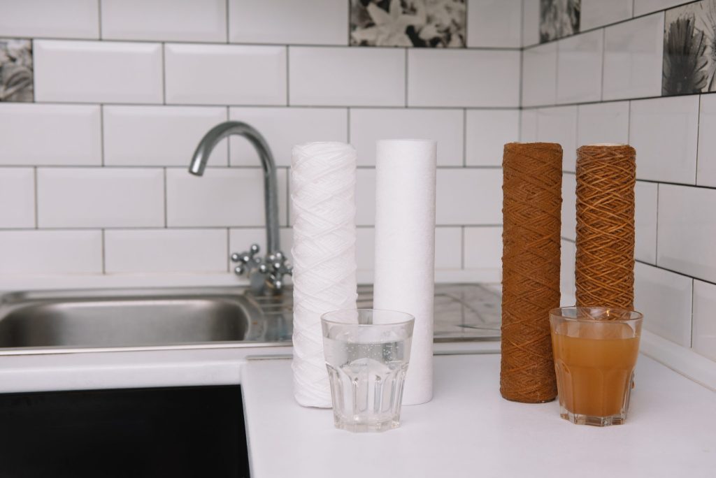 New and spent filter cartridges beside clear and discolored water.
